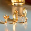 Macro detail of gold-plated geometric earrings set with sparkling orange zircon stones - Amber Orange Style (AEH70352-5)