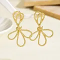 Detailed close-up of golden spiral bow earrings hanging on a white geometric stand - Champagne Gold Twisted Spiral Floral (EH5351)