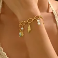 Gold ocean charm bracelet with turtle, shell, and pearl details on wrist - Ocean Style Charm Bracelet (SL7837)