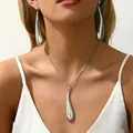 Macro shot of silver teardrop pendant and pearl drop earrings on a silk model - Artificial Pearl Embellished Round Toe Style (XL5307-2) / Silver