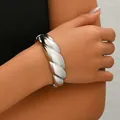 Close-up of a wide twisted silver metal cuff bracelet with a polished mirror finish - Silver