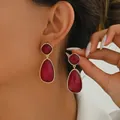 Detail view of red teardrop gemstones in gold settings worn by a model in soft light - Burgundy (EH4968-4)