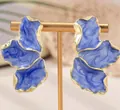 Dettaglio ravvicinato di orecchini dorati ondulati con smalto marmorizzato blu scuro - Stile Blu Profondo (EH4785-1)