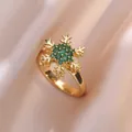 Gouden sneeuwvlok ring met groene zirkoon op een roze satijnen achtergrond - Smaragdgroene Sneeuwvlok Open Ring (J0210)