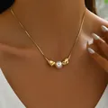 Long gold snake chain necklace with white pearl and pleated metal charm on model - Gold Style (XL5417-3)