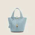 Close-up of sky blue lychee grain leather bucket bag with golden padlock and metal hardware - Light Blue