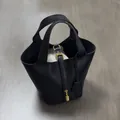 Close-up of black litchi grain leather tote with golden padlock and canvas inner pouch - Black