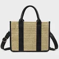 Detailed macro view of woven straw tote bag with black leather straps and gold metal buckles - Woven Black