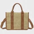 Detail of woven straw tote bag featuring brown leather trim and adjustable canvas strap - Straw Brown