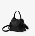 Detail of black pebbled leather bucket bag with top handle and metal hardware hooks - Black