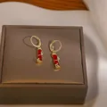 Orecchini a bambù dorati con pietre rosse e cristalli su una scatola di pelle marrone - Orecchino a Cerchio in Bambù (D0304) / Rosso
