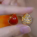 Eleganti orecchini a goccia dorati con gemma rossa e pavé di strass in uno scatto macro - Orecchini a Bottone a Goccia Asimmetrici (D0788) / Oro Rosso Bianco