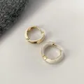 Orecchini a cerchio dorati minimalisti con smalto crema su sfondo in pelle bianca - Bianco