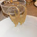 Dettaglio di orecchini a cerchio dorati con nappe a catena fitta su piatto bianco - Cerchio Con Nappa - Oro