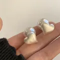 Brushed heart-shaped earrings with large white pearls shown on hand for scale - Brushed Heart Style (D0456)