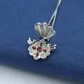 Vista macro di un ciondolo a conchiglia argento con gemme rosse e rilievo inciso - Rosso