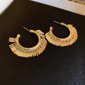 Dettaglio macro di orecchini a ventaglio dorati a forma di C su superficie nera - Decorazione in Strass / Stile Nappina a Barra con Frange Oro(D0472)