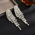 Dettaglio di orecchini a nappa dorati con cascata di cristalli brillanti taglio baguette - Orecchini pendenti lunghi in strass a cascata dorata (D0697) / Oro