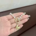 Dettaglio della collana di perle bianche con ciondolo a farfalla dorata e chiusura a T - Farfalla Occhio di Gatto Perla (L0187)