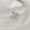 Dettaglio anello a doppia piuma d'argento con zirconi pavé su seta bianca morbida - Squisito Anello d'Argento