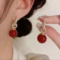 Dettaglio ravvicinato di orecchini vintage in oro con perle rosse e zirconi lucidi - Stile Anelli Intrecciati con Sfera Rosso Scuro (D0800)