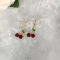 Dettaglio ravvicinato di orecchini a ciliegia placcati oro con zirconi rossi e verdi - Orecchini a foglia verde smeraldo con zirconia rossa (Orecchini D0897)