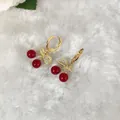 Dettaglio di orecchini a ciliegia rossi con cerchi dorati e foglie di zirconi lucidi - Orecchini a ciliegia con fiocco e perla rossa con strass (D1316)