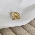 Dettaglio di un anello dorato regolabile con design a goccia 3D su tessuto di seta - Cuore a Superficie Liscia (Z0298)