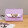 Detail of purple lychee leather wallet with white V-stripe and golden bow clasp - Purple