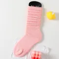 Schicke hellrosa gerippte Strickstulpen mit Markenanhänger auf weißem Hintergrund - Einheitsgröße / Hellrosa