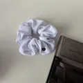 Soft white plush scrunchie with round metal tag and fluffy velvet texture - White