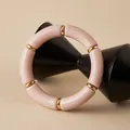 Close-up of bohemian pink acrylic tube beads and gold metal spacers on a display stand - Pink (AB0079-3)