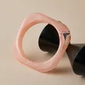 Detail view of a wide pink marble pattern acrylic resin bangle on a geometric stand - Pink Quicksand (AB0086-2)