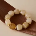 Détail de perles en acrylique crème et d'un séparateur doré sur une surface en bois - Style Marbre Beige Crème (AB0095-2)