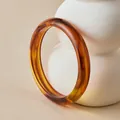Close-up of bohemian amber resin bangle with retro tortoiseshell texture on beige surface - Amber Tortoiseshell Pattern (AB0093-3)