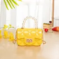 Mini yellow jelly handbag with pearl handle and diamond quilted pattern on wood surface - Yellow