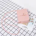 Petit sac carré rose clair avec anneau doré et rivets sur fond en tissu à carreaux - Rose