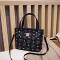 Borsa a secchiello nera con stampa monogramma e borchie dorate in un set elegante - Nero