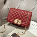 Deep red quilted crossbody bag with golden chain and vintage metal lock on a sofa - Burgundy