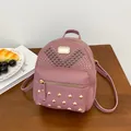 Pink faux leather mini backpack with golden heart rivets shown in lifestyle setting - Dusty Pink