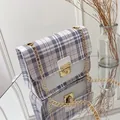 Purple and white checkered crossbody bag with gold chain strap on mirror surface - White