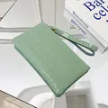 Light green crocodile pattern clutch bag with wristlet strap on a mirror background - Light Green