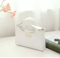 Detalle de bolso de hombro blanco trenzado con elegante placa de metal dorado central - Blanco