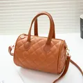 Brown quilted boston bag with gold hardware and a removable strap on a bright surface - Brown
