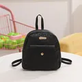 Mini mochila negra con relieve floral y bolsillo con botón dorado en una mesa blanca - Negro