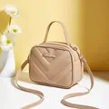 Kleine beige crossbodytas met V-textuur en metalen logo op een gele achtergrond - Khaki