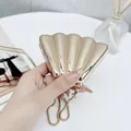 Elegant gold shell shaped evening bag with snake chain strap held by a hand - Shell Inlay Gold Color