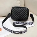 Elegante bolso bandolera acolchado negro con costuras en V y correa ancha de tela bordada - Negro