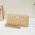 Cartera larga de paja tejida beige con adorno de mariposa blanca y correa de muñeca - Albaricoque