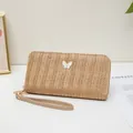 Cartera larga de paja tejida en beige con un colgante de mariposa blanca y asa de mano - Marrón